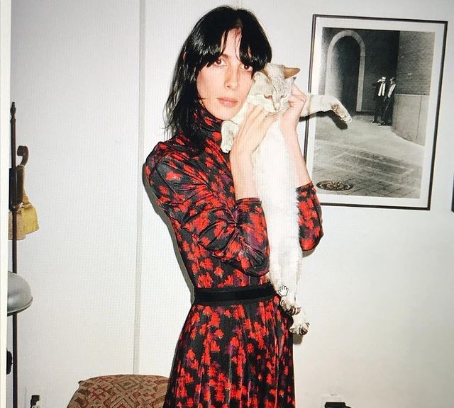 Sonja Kinski posing for a photoshoot by carrying her cat by wearing spotted dress.